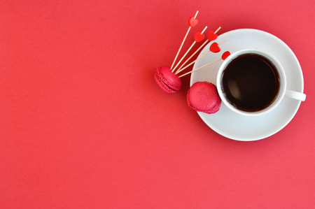 Bright concept for Valentines day. Cup of tea and raspberry macaroons on red background. Trending Panton colorの写真素材