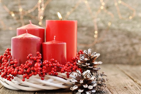 Fourth Advent - Four candles in a white wreath with red berries on a wooden rustic background with lights. advent calendar for Christmas.の写真素材