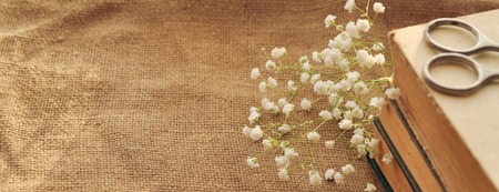 Vintage spring background with white flowers, a yellowed old books and the scissors on the burlap. closeup. toned. bannerの写真素材