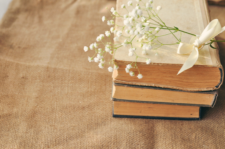 Vintage spring background with white flowers, a yellowed old books on the burlap. closeup. tonedの写真素材
