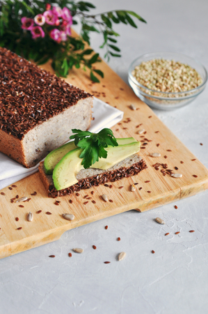 Healthy and proper Breakfast. Sandwich with avocado and homemade bread on sourdough of green buckwheat with flax seeds, sunflower. Raw and vegan food.の写真素材