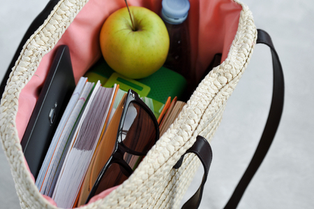 Stylish fashionable wicker bag with textbooks and notebooks, lunchbox and green Apple, water for a snack and sunglasses. Admission to University and summer session. Copy spaseの写真素材