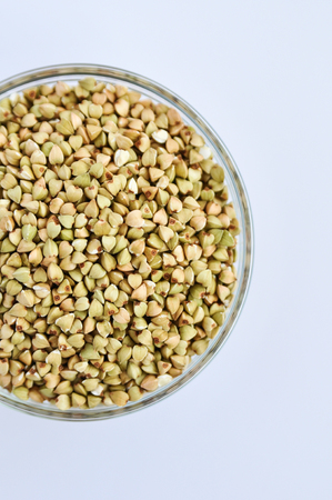 Green buckwheat untreated in a glass bowl for a healthy lifestyle on a white background. Copy spaceの写真素材