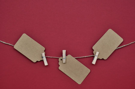 Paper craft discount labels are attached with clothespins to the rope on a red background. copy...