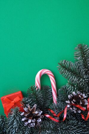 Postcard in the colors of Christmas mood: red gifts, berries, sweets and green fir branches, background.の写真素材