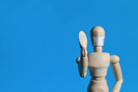 A figure of a man made of wood in a medical mask holds his hands up, warning of danger. Coronavirus, pandemic and epidemic conceptの写真素材