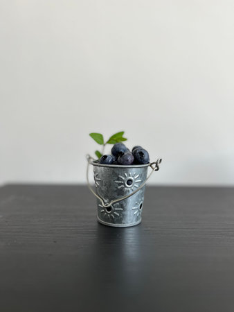 Blueberries in a metal bucket on a black wooden table with copy spaceの写真素材