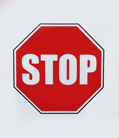 A red stop sign on a white background in close-up.