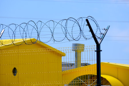 Industrial gas equipment is painted yellow behind barbed wire.の写真素材