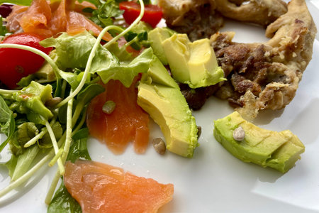 On a white plate - a salad of tomatoes, green arugula, avocado, salmon and mushroomsの写真素材