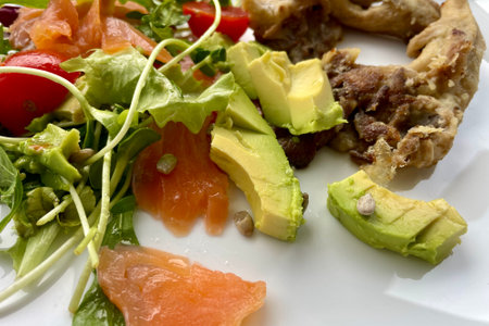 On a white plate - a salad of tomatoes, green arugula, avocado, salmon and mushroomsの写真素材