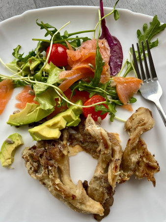 On a white plate - a salad of tomatoes, green arugula, avocado, salmon and mushroomsの写真素材
