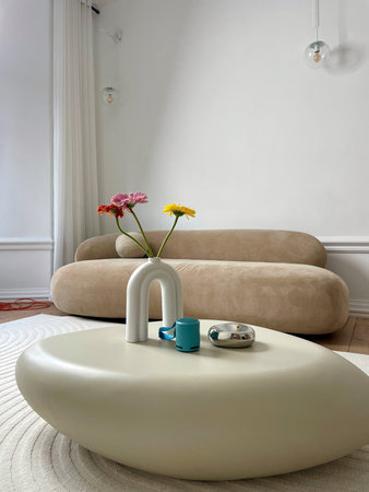 Gerbera flowers and a cup of coffee on a table in a beige bedroom