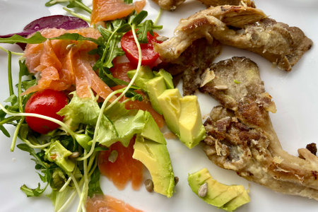 On a white plate - a salad of tomatoes, green arugula, avocado, salmon and mushroomsの写真素材