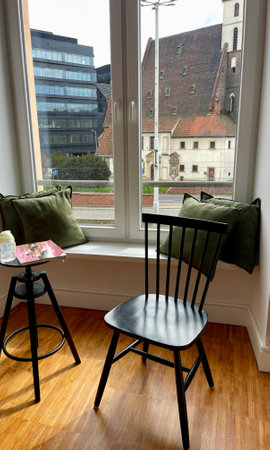 a wooden chair in front of a window with a view of the city, as part of the interiorの写真素材
