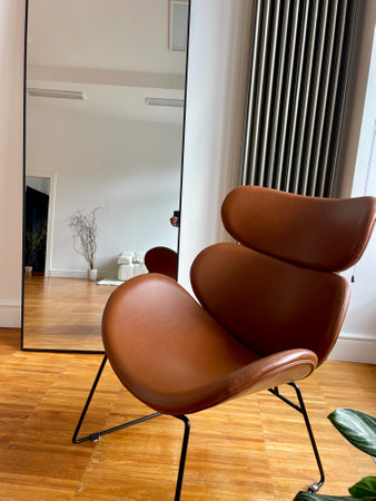 A brown leather chair and a large mirror as part of the decor in the interior of the roomの写真素材