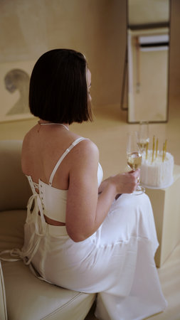 Birthday girl, young beautiful woman in festive attire posing with a glass of champagne wineの写真素材