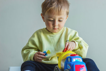Little boy playing with toy car, child developing