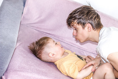Teenage boy happily playing with his younger brother while looking after him