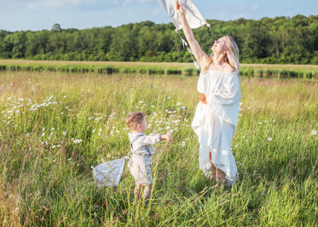 A little child and his mother are having fun in the meadow, flying a kiteの写真素材
