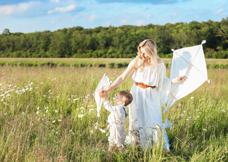 Beautiful young mother and child flying a kite in the meadow.の写真素材