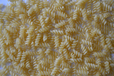 Pasta spirals spread out on a table used as a background or decoration item.の写真素材