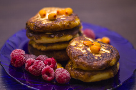 Baked cottage cheese with raspberries and sea buckthorn on a purple plateの写真素材