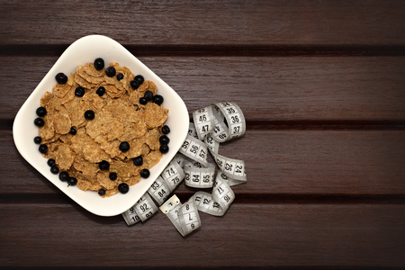 Corn flakes with berries in white plate on brown wooden boards. The sky lies a meter. Background, texture, close-up. View from aboveの写真素材