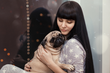 The girl is sitting in an embrace with a pugの写真素材