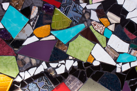 Multicolored mosaic of broken plates, background. Slices of broken ceramic tableware
