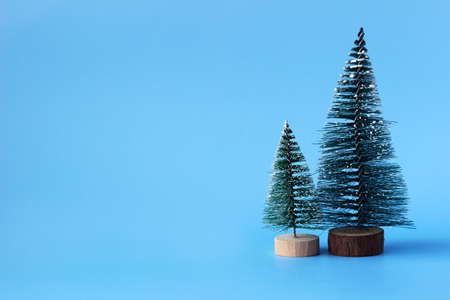 Two artificial Christmas trees on a blue background, place for text. New year conceptの写真素材
