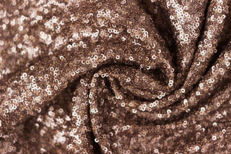 Gold brown sequins, background. Shiny background, blurred. Twisted fabricの写真素材