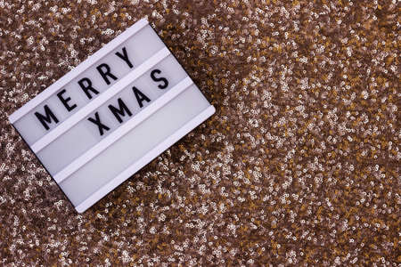 Light board inscription Merry Xmas on a gold sequin background. Winter holidayの写真素材