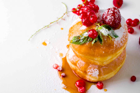 Morning breakfast with mini donuts and berries on plate under powdered sugar on background.