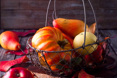 Autumn leaves on wooden table. Fruits and vegetables, apple, pear, pumpkinの写真素材