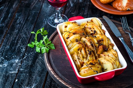 Sliced baked potatoes over wooden background. Rustic style.の写真素材