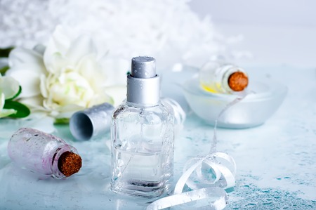 perfume bottles surrounded by flower petals and water backgraundの写真素材