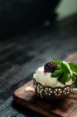 vanilla ice cream with mint leaves in an iron bowl on dark wooden backgroundの写真素材