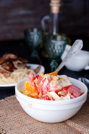 Salad with fresh cabbage, tomato, cucumber and herbs on the plate on a tableの写真素材
