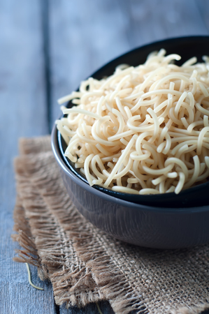 Raw uncooked pasta in bowl over wooden backgroundの写真素材