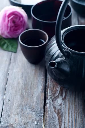 asian tea set and rose petals on the wooden backgroundの写真素材