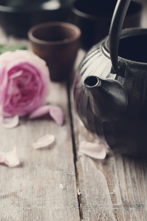 asian tea set and rose petals on the wooden backgroundの写真素材