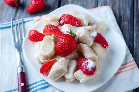 Cottage cheese dumplings with strawberries on background top view with sour creamの写真素材