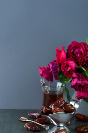 Traditional arabic tea and dry dates. roses in the backgroundの写真素材