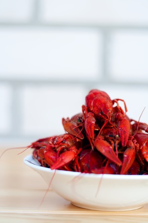 Red boiled crayfish in a white bowl on the tableの写真素材