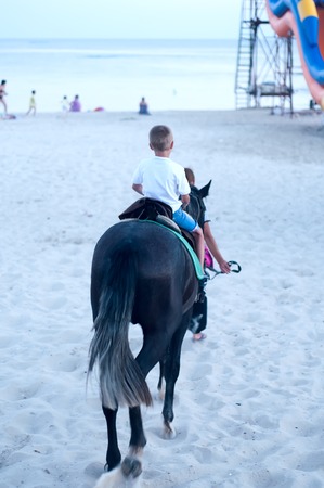 Small little boy riding his horse in evening lightの写真素材