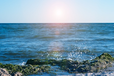 Big wave splashing. Sea water beating against the rocks and cliffs. Blue sky above the beach in the sun zenith refreshing drops of ocean water.の写真素材