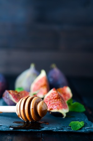 honey stick, Ripe purple figs and mint on dark slate board on wooden backgroundの写真素材