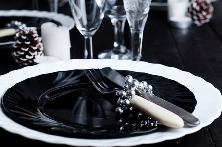 Christmas table setting with pine cones and candles on a dark backgroundの写真素材