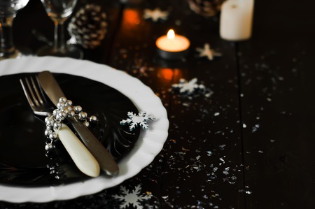 Christmas table setting with pine cones and candles on a dark backgroundの写真素材
